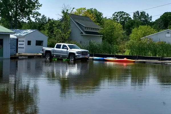 A truck sits in flood waters with two kayaks nearby.